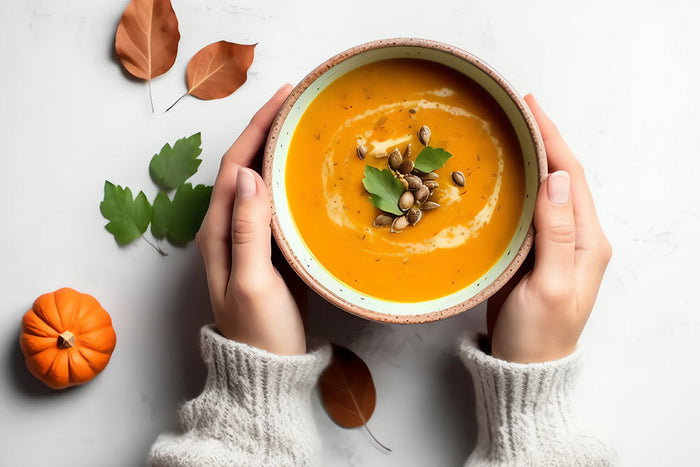 A female grabbing a festive and healthy pumpkin soup filled with fiber.