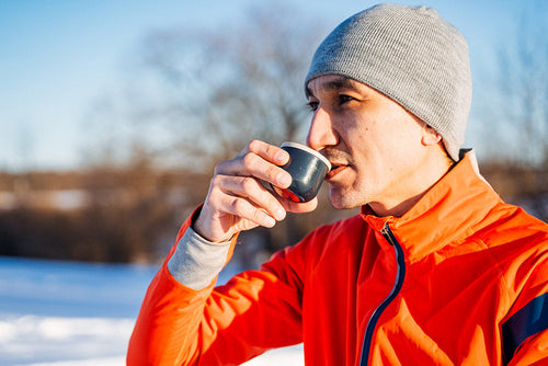 A man enjoys a warm drink outdoors after a winter workout, symbolizing the balance of energy and recovery in Your Daily Reset: Inflammation + Energy.