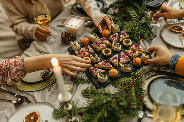 reaching for festive holiday appetizers at a decorated table, highlighting mindful choices during seasonal gatherings.