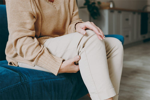 Person holding their knee while seated, representing the importance of calming inflammation and protecting joint health to support comfort and mobility.